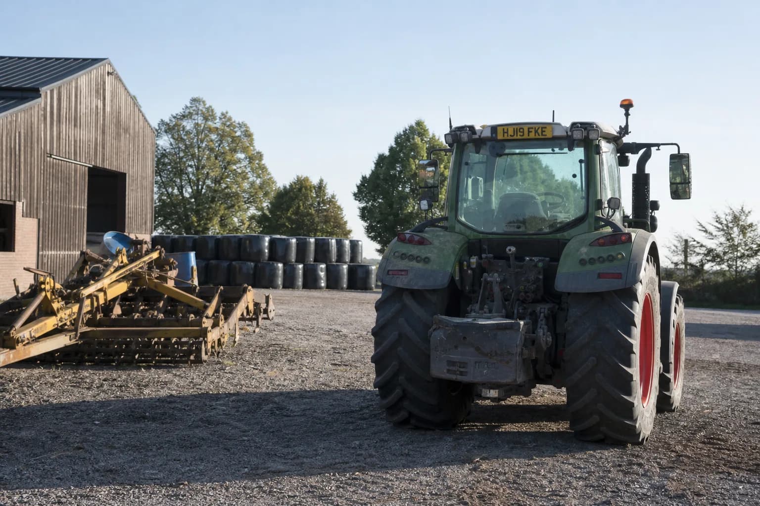 Rural farm yard with agricultural machinery and a tractor