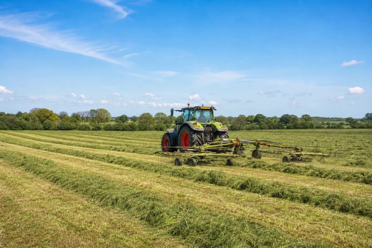 Tractor carrying out field work on farmland under a clear sky